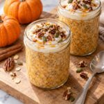 Two jars of pumpkin spice overnight oats topped with Greek yogurt, pecans and pumpkin seeds