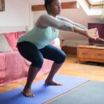 Woman doing a bodyweight squat on a yoga mat in her living room